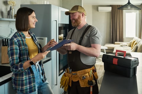 Homeowner signing documents with repairman in kitchen