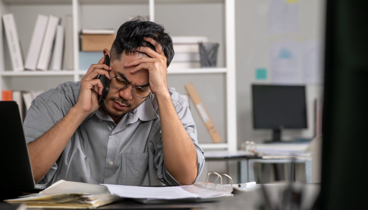 Stressed businessman talking on the phone feeling overworked and burned out